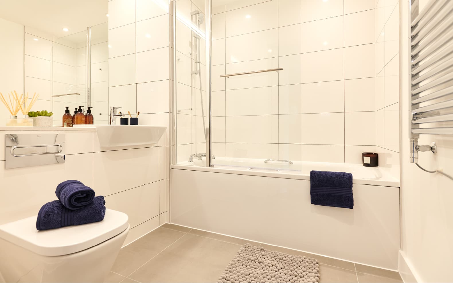 bathroom suite with towels piled on top of toilet